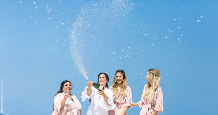 Bride celebrating with her bridesmaids on a Caribbean beach with champagne during a destination wedding in Punta Cana.